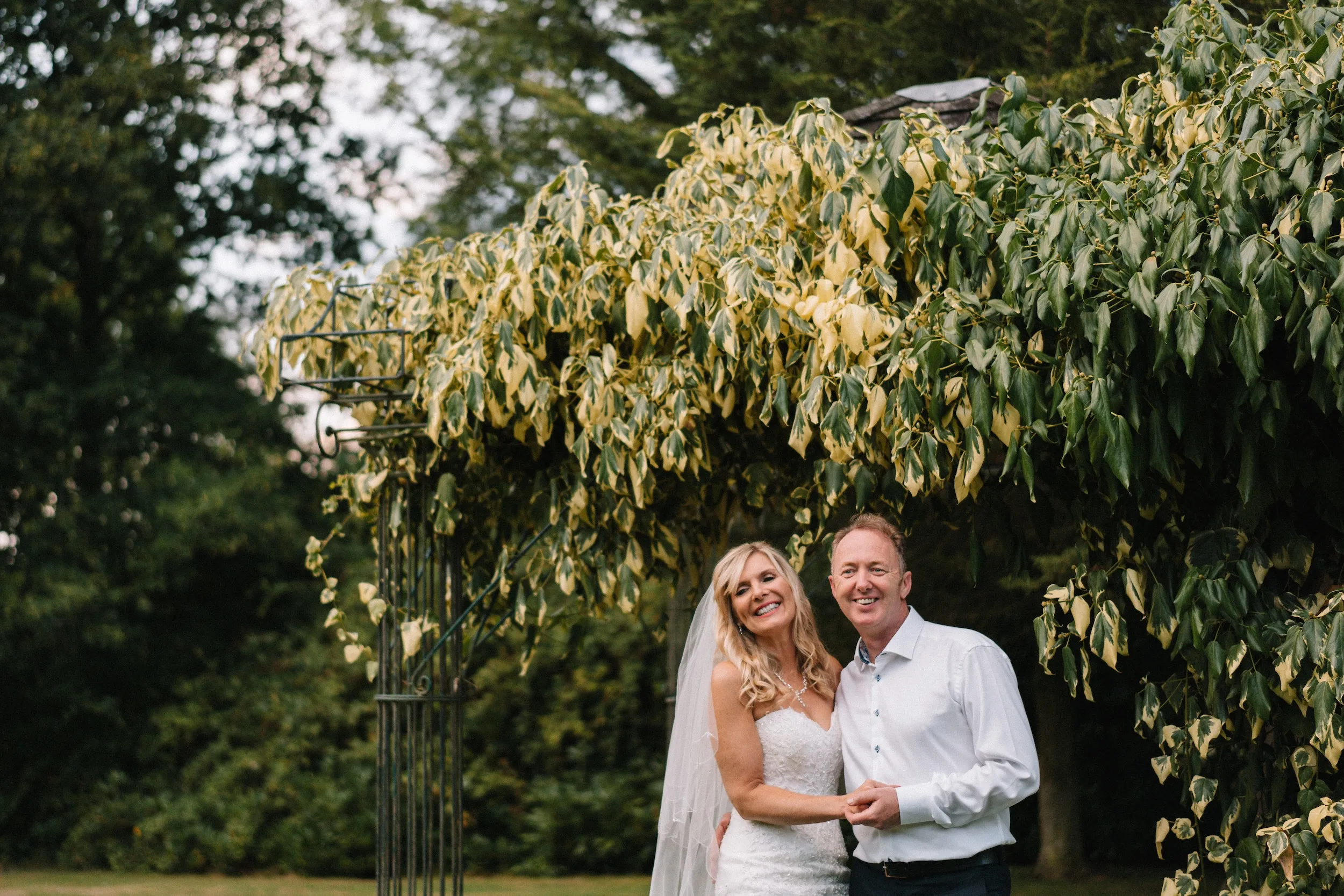 Mark and Fiona under a garden arch of green leaves