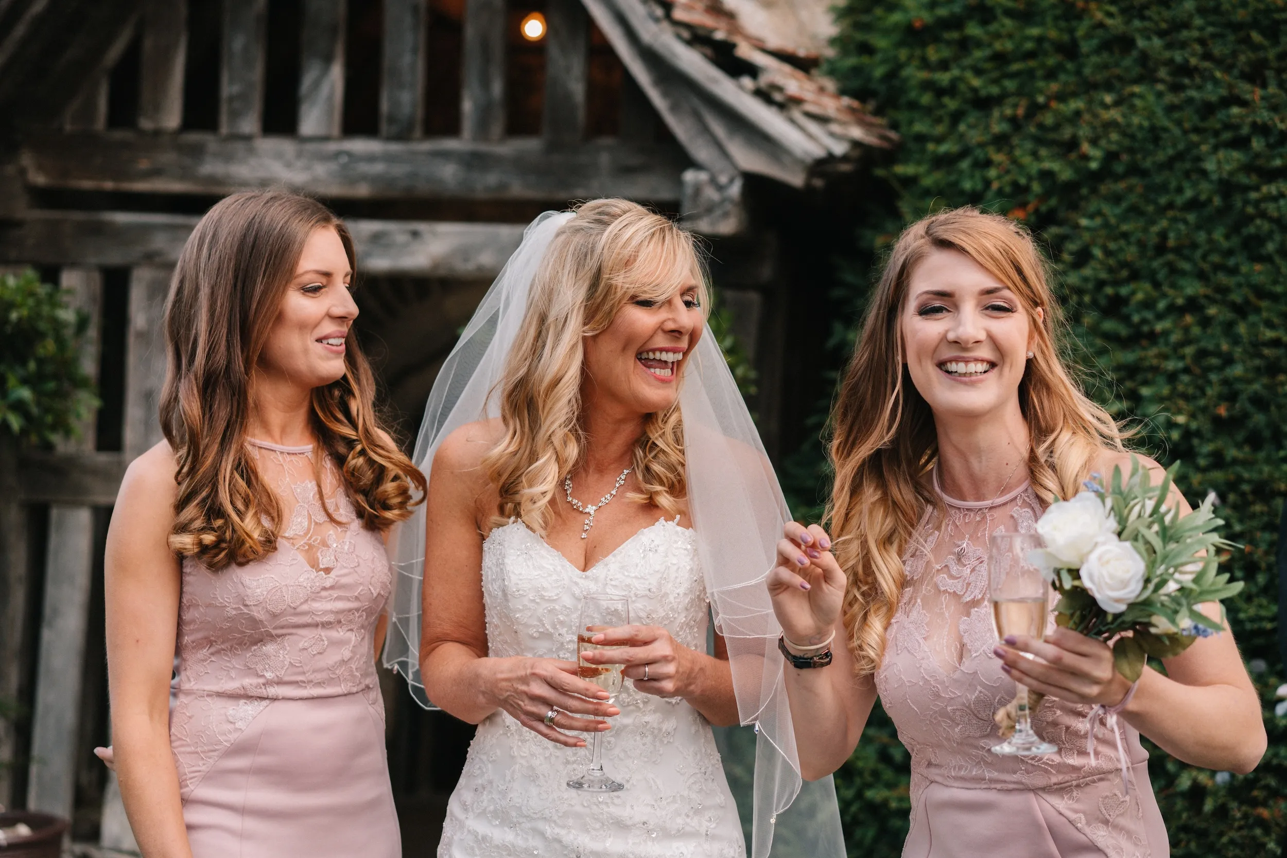 Fiona laughs with her two bridesmaids beside the timber porch