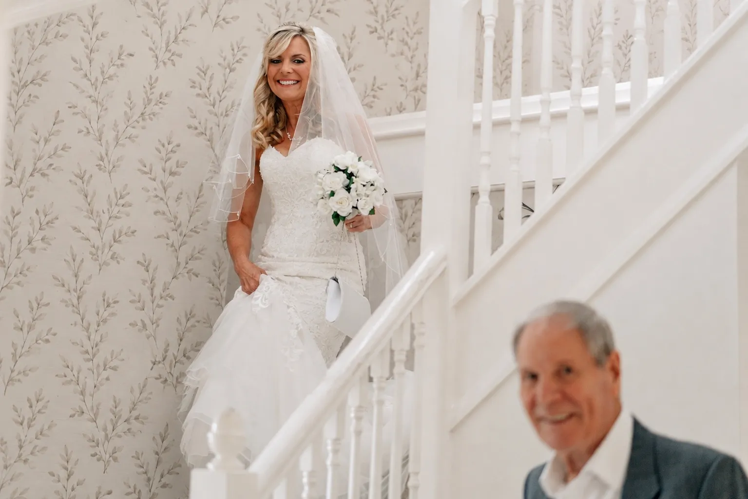 Fiona comes down the stairs in her dress as her father waits at the bottom