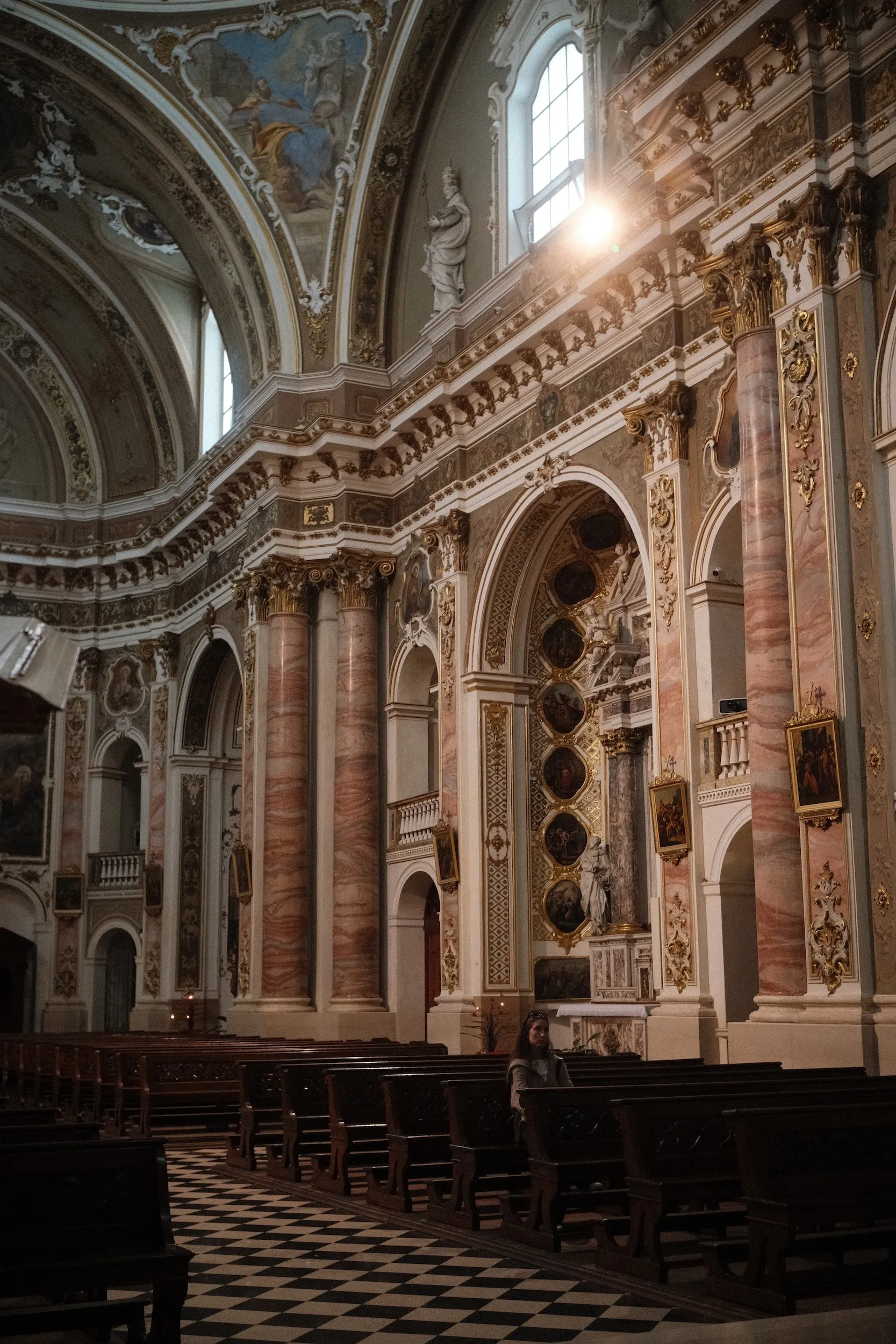 The ornate nave of a Catholic church, lit from the side
