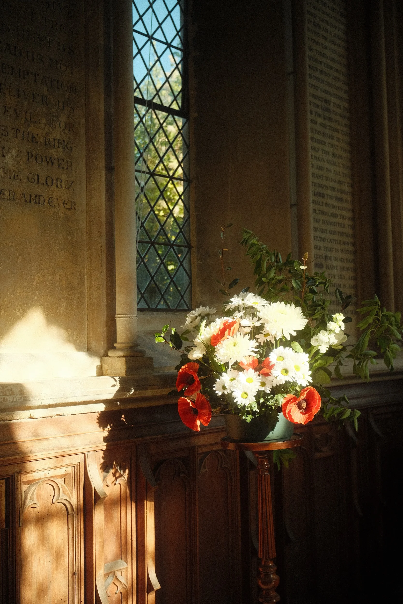 Poppies and daisies catching a shaft of window light in a church