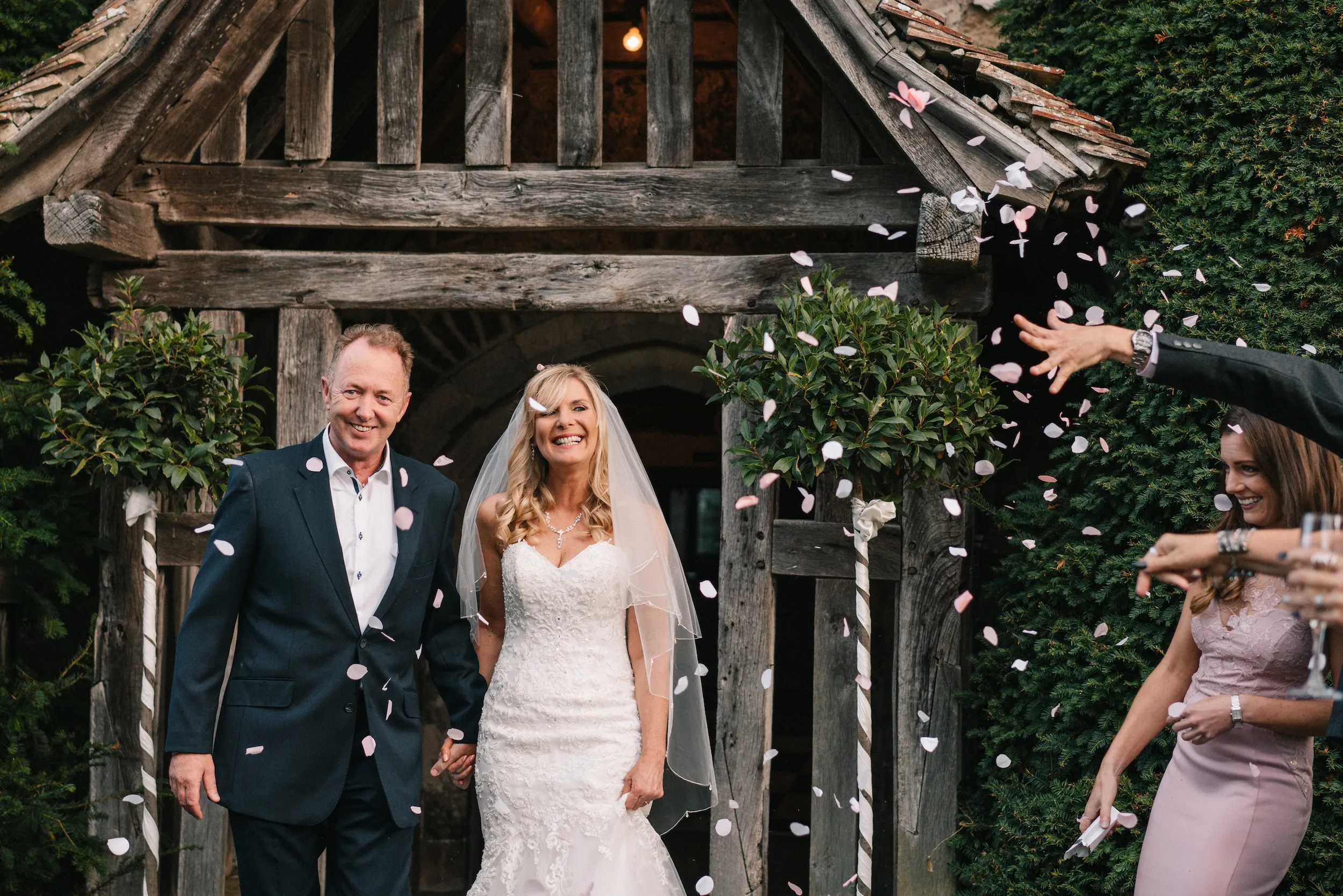 Guests throw petals as Mark and Fiona leave through the timber porch