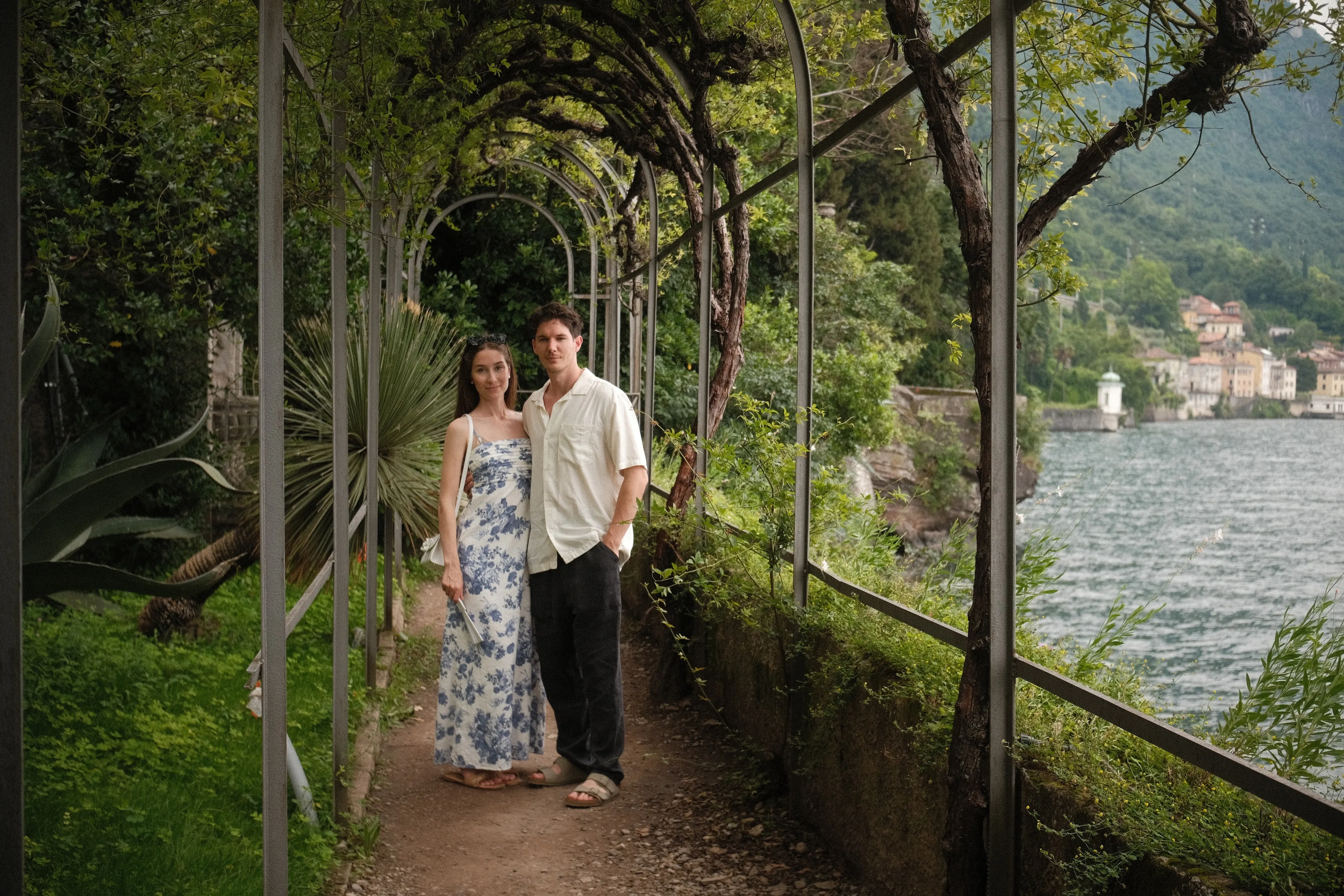 A couple stands under a garden pergola above an Italian lake