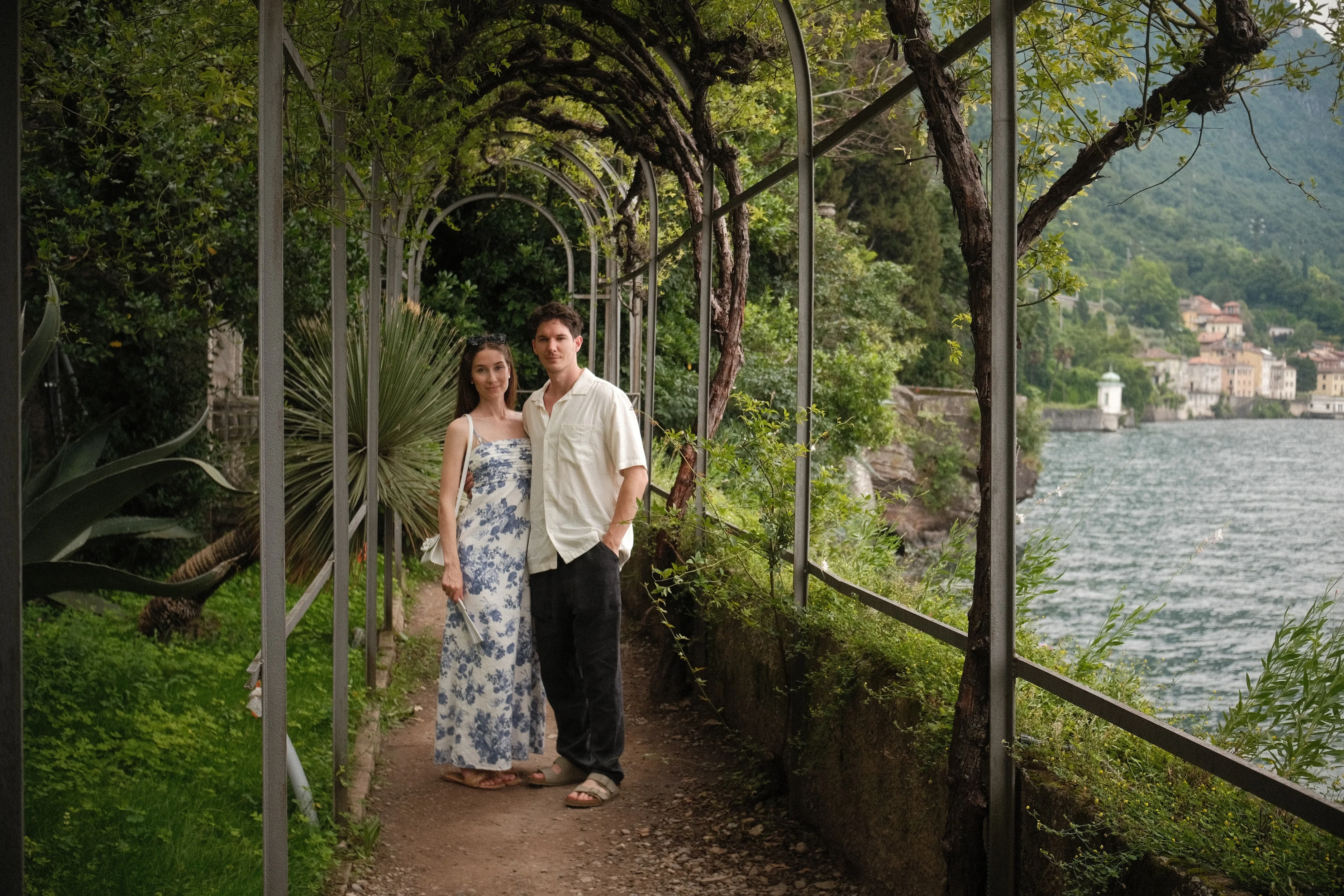 A couple stands under a garden pergola above an Italian lake