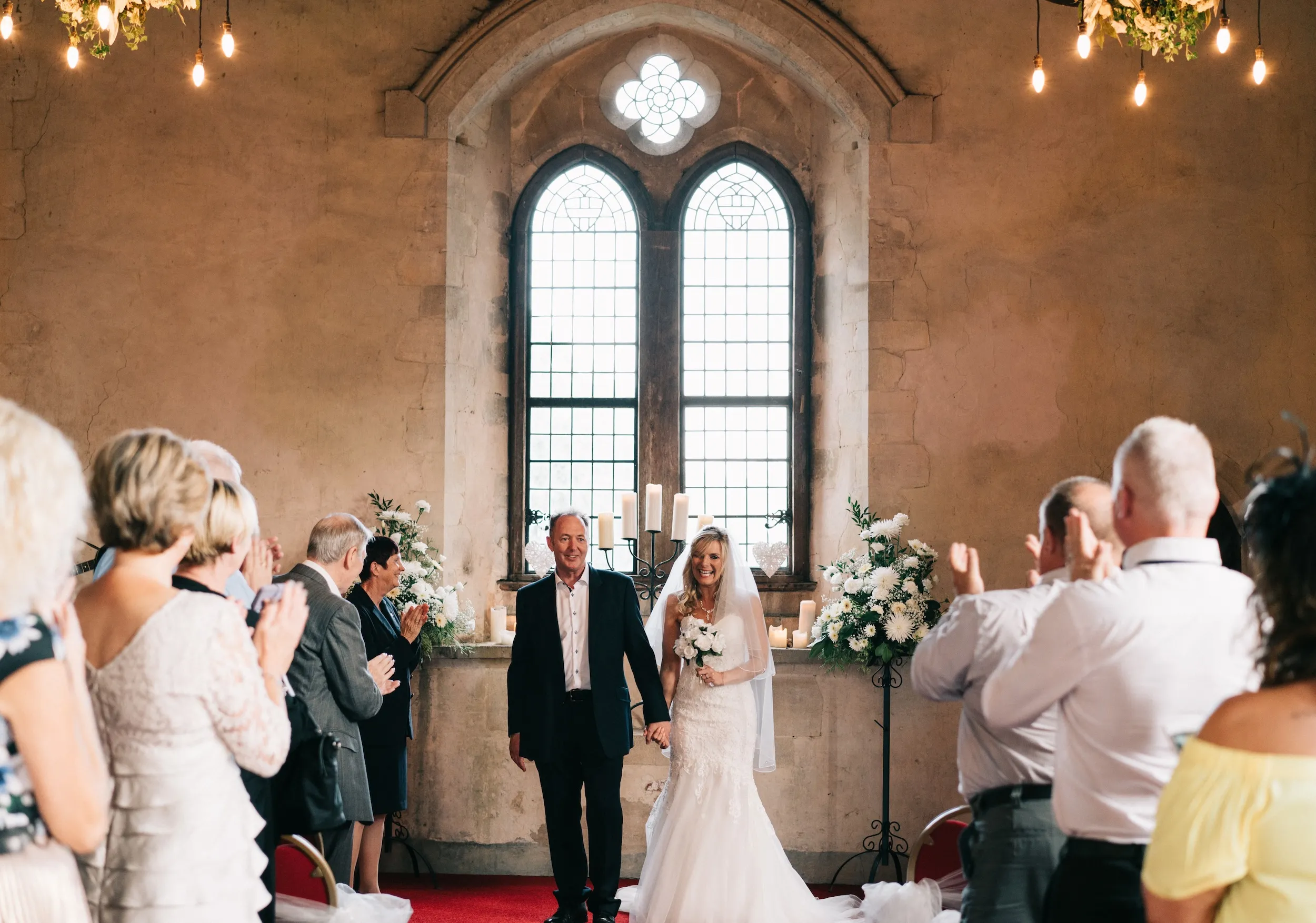 Guests stand and applaud as Mark and Fiona are married at the front of the Great Hall