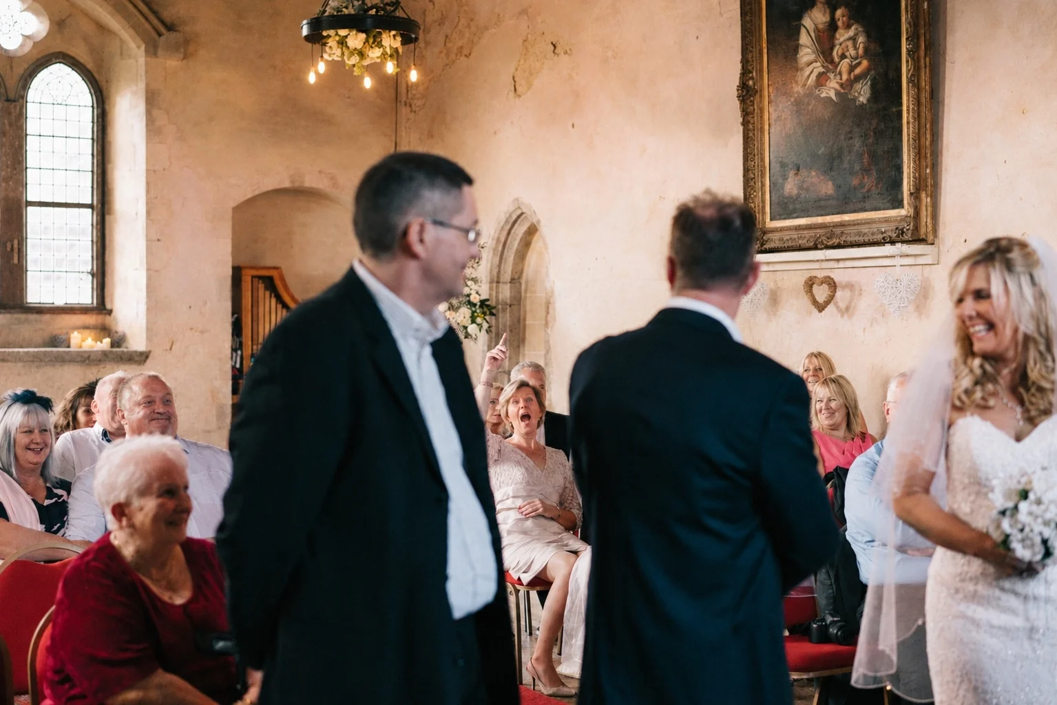 Guests laugh during the ceremony as Fiona smiles at the front of the hall