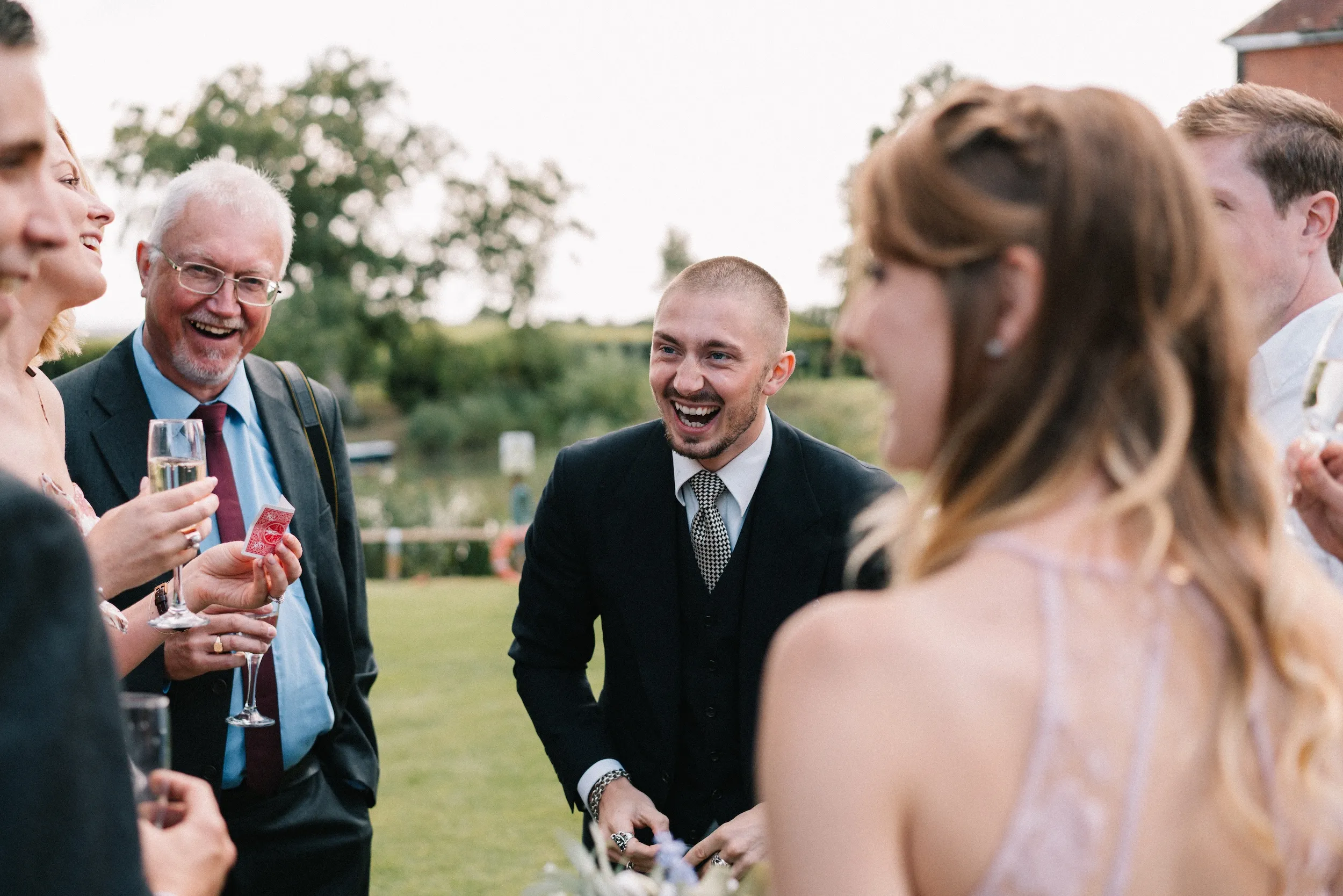 Guests laugh together on the lawn during the drinks reception