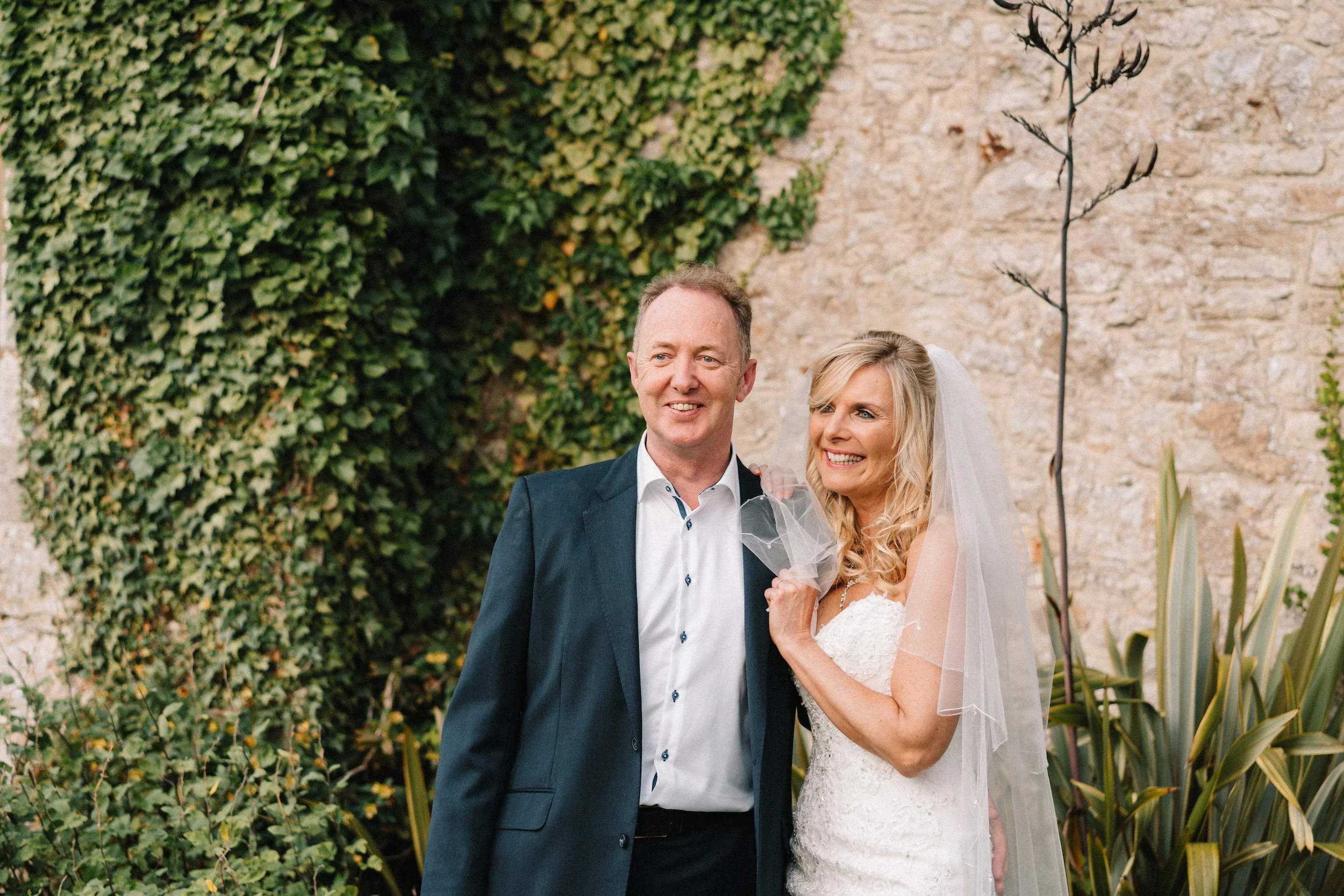Mark and Fiona against an ivy-covered stone wall in the gardens