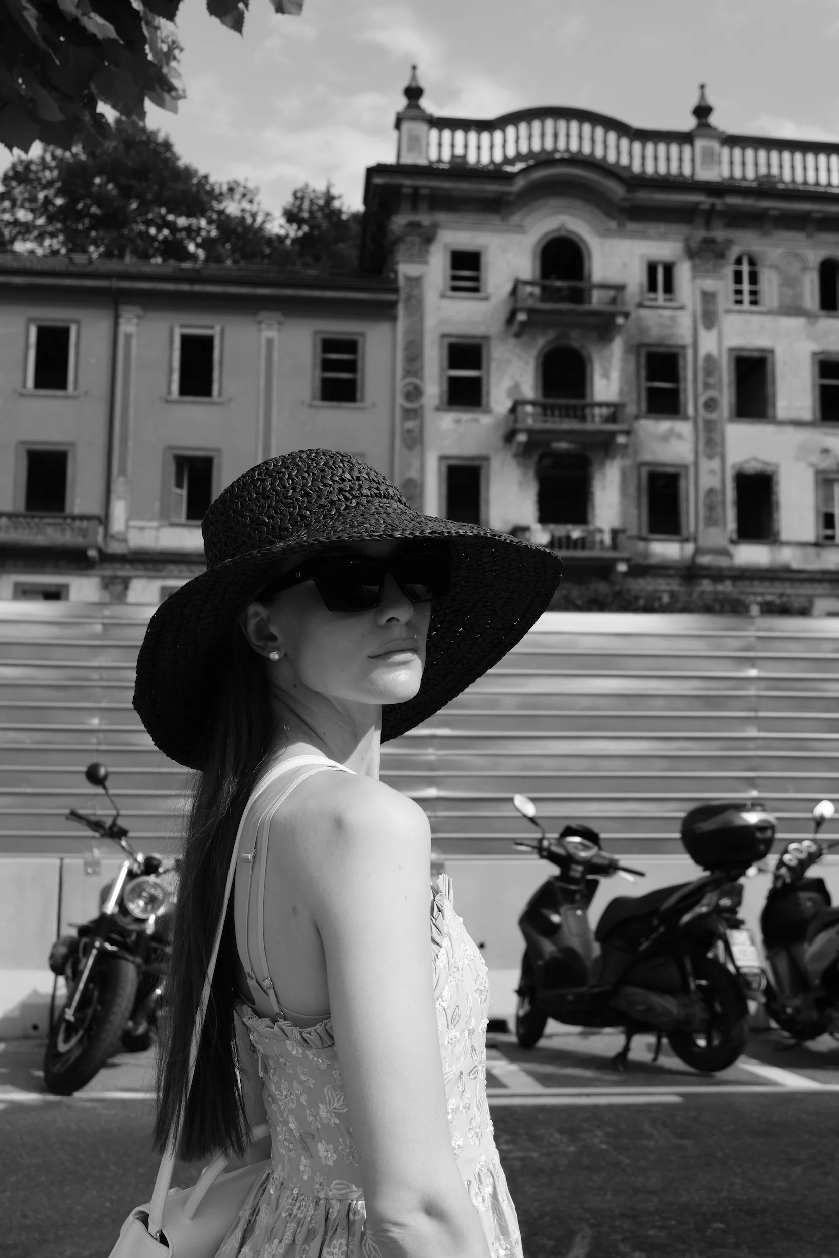 Black and white portrait of a woman in a wide sun hat in an Italian street