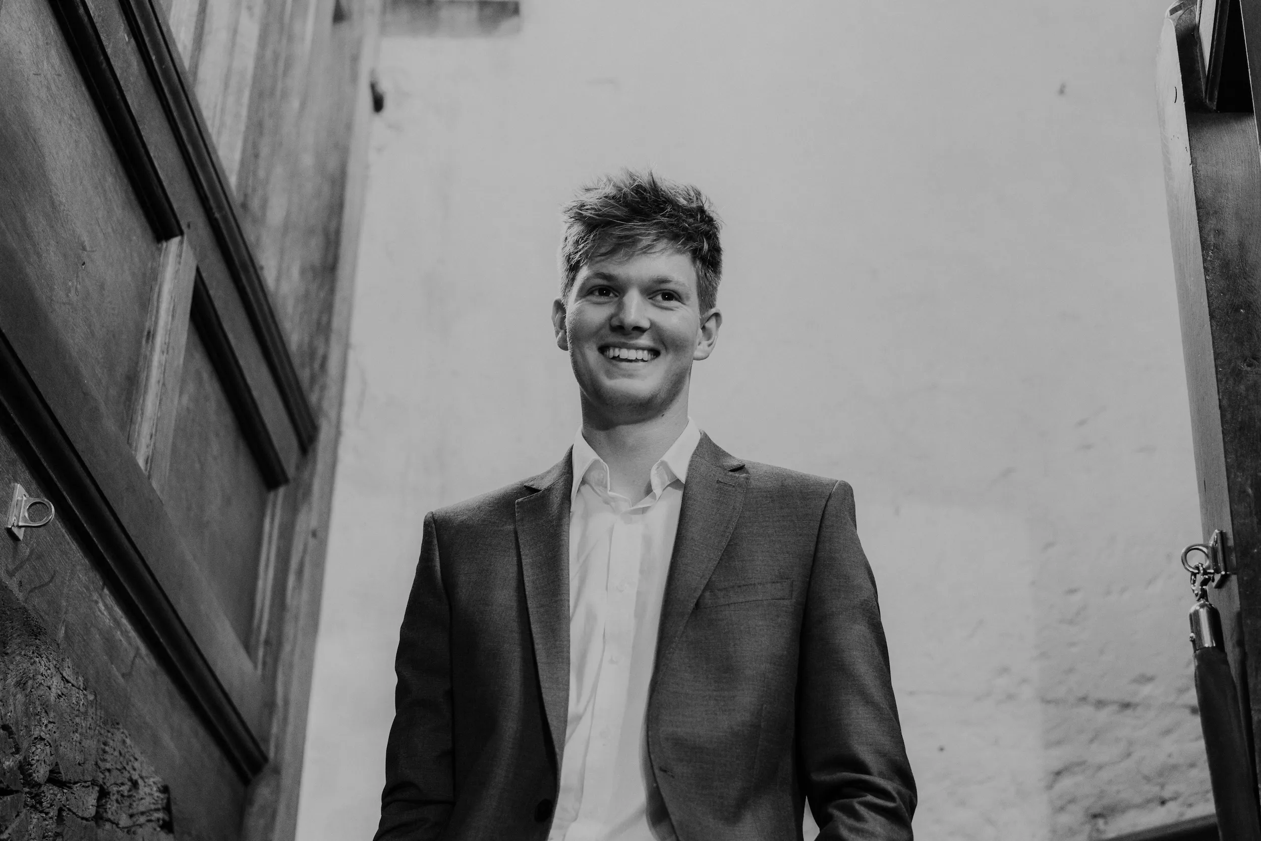 Black and white photograph of a young guest smiling in an old priory doorway